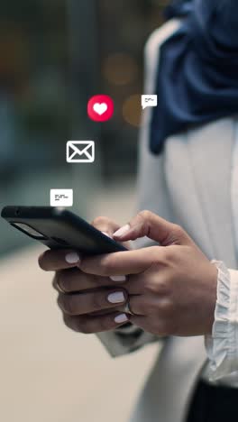 vertical video close up of muslim businesswoman standing outside city offices looking at mobile phone with motion graphics emojis showing multiple networking messaging and social media notifications