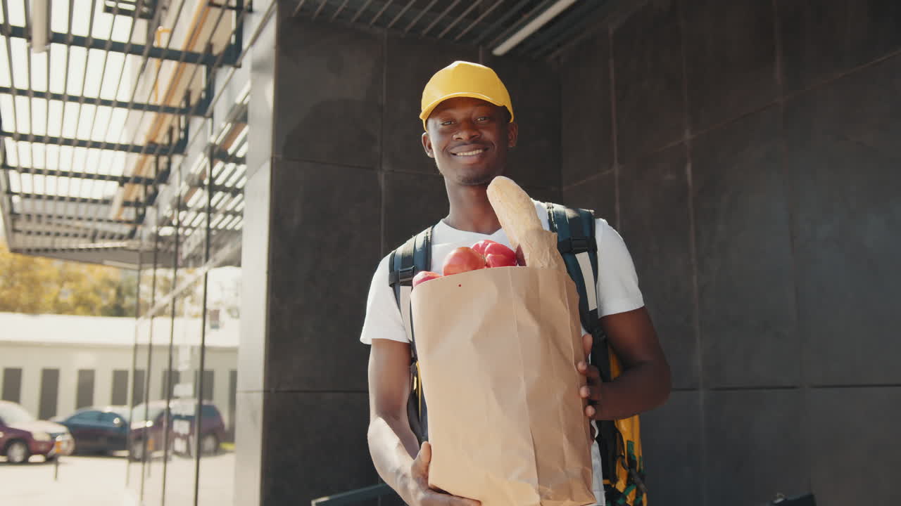 Smiling delivery man holding a grocery bag