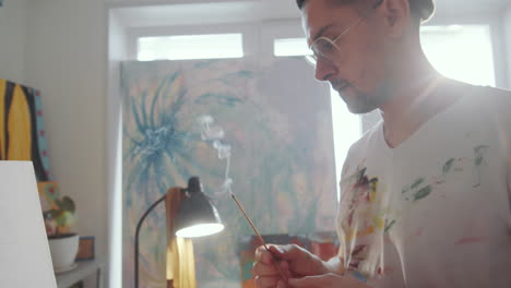 Man-Lighting-Incense-Stick-and-Drawing-Picture-in-Art-Studio