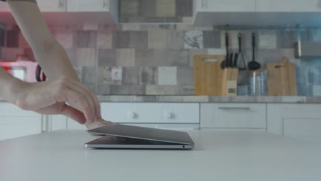 person opening laptop in a kitchen