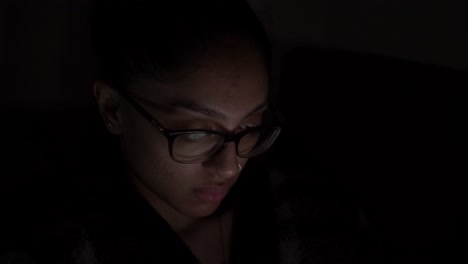 joven mujer asiática del reino unido con gafas viendo videos en el móvil por la noche