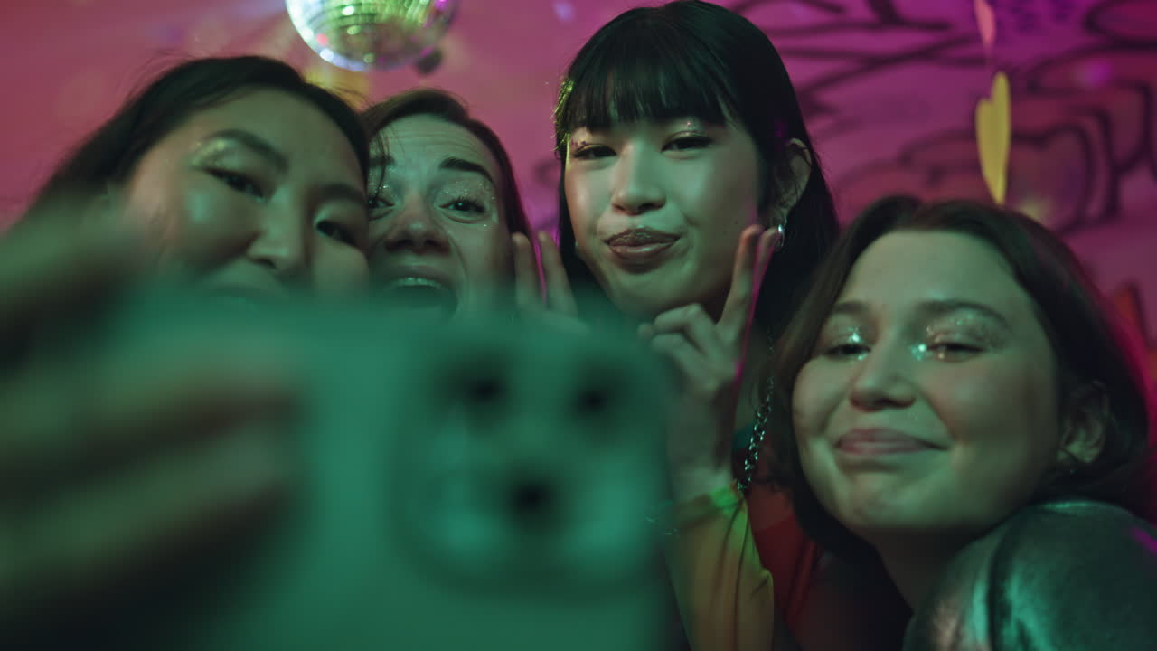 Joyous group taking selfie on smartphone at nightclub party closeup. Happy girls