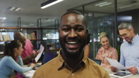 portrait of african american businessman smiling over diverse business colleagues talking