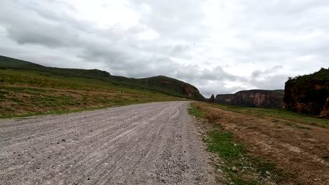 POV-Personal-point-of-view-shot-from-a-bicycle-as-going-forward-on-a-rural-road-towards-mountains