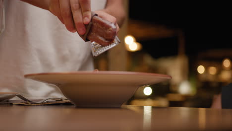 waiter grating bottarga on top of the dish for elegant gourmet dinner