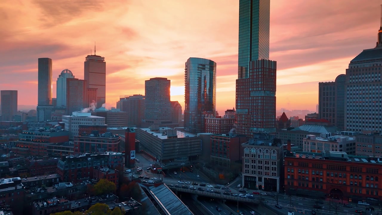 Wolkenkrabbers van Boston tegen een achtergrond van een oranje en roze lucht. Verkeer beweegt zich over de wegen van de metropool. Stadsgezicht bij schemering