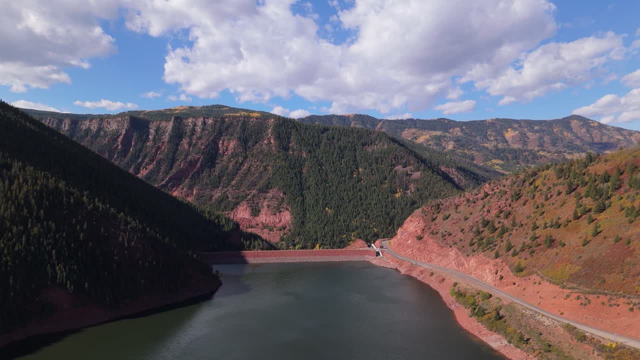 Parallax drone shot of dam with fall mountains