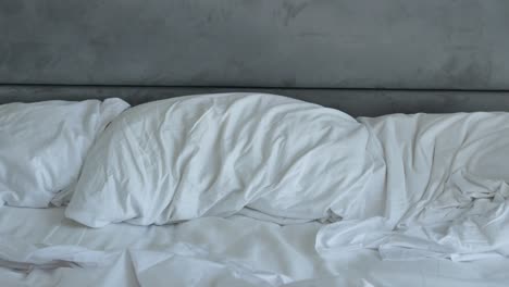 unmade bed with white sheets and pillows