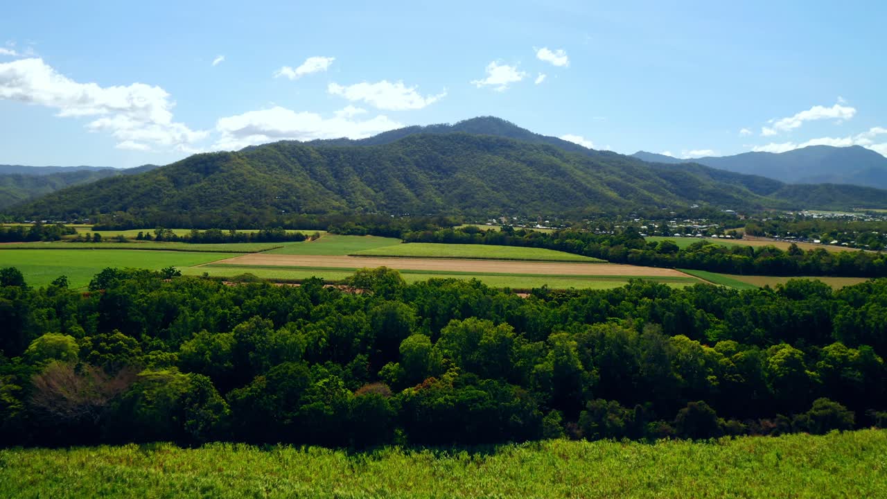 vibrantes campos agrícolas y montañas en cairns, queensland, australia durante el día - toma aérea de drones