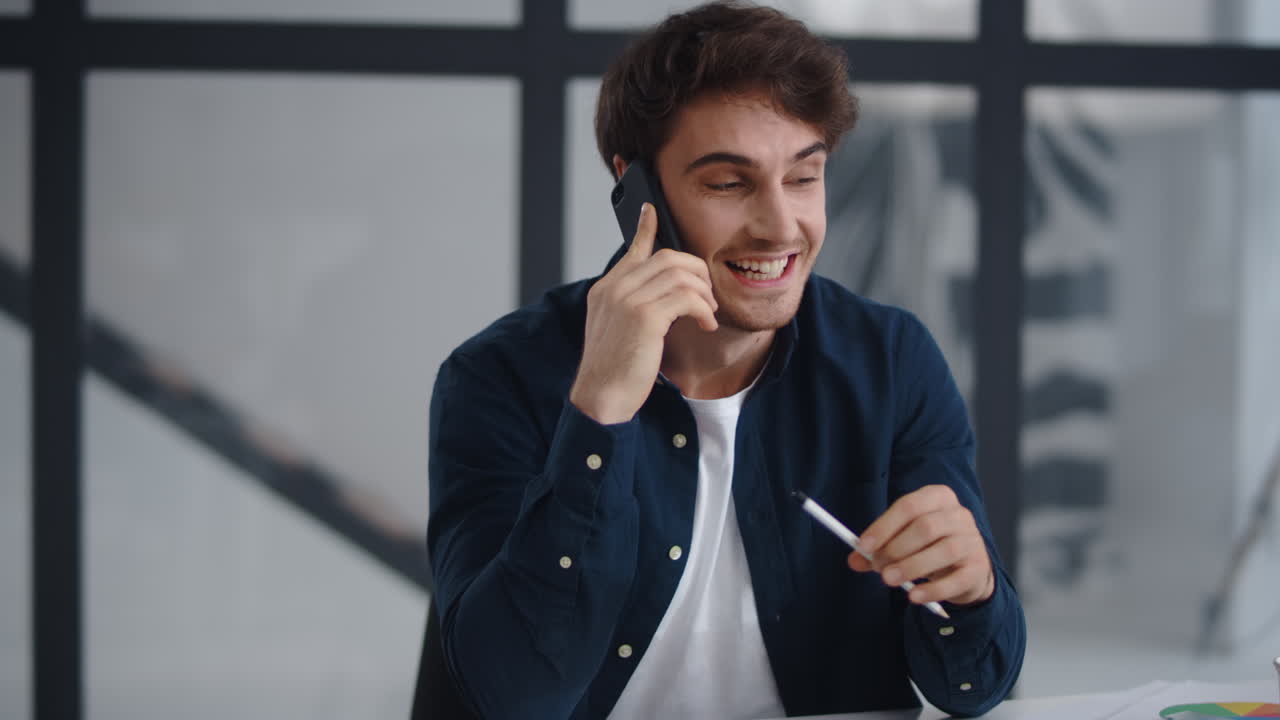 hombre de negocios sonriente hablando por teléfono móvil en la oficina. hombre terminando una llamada telefónica