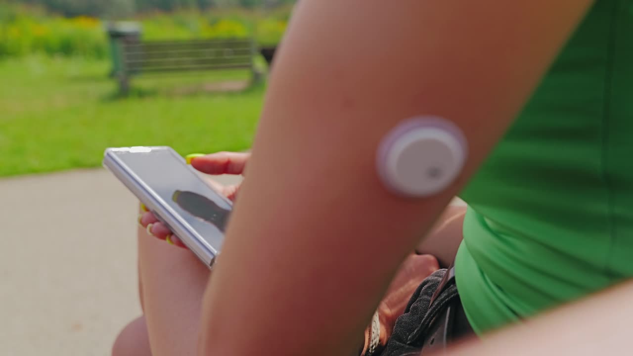 Camera shifts from arm sensor to phone as woman reviews glucose data real time