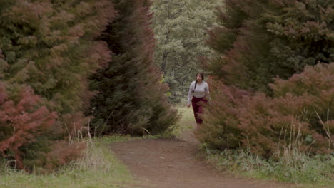 A young woman is seen climbing a forest trail, presumably with the intention of exploring the surrounding area