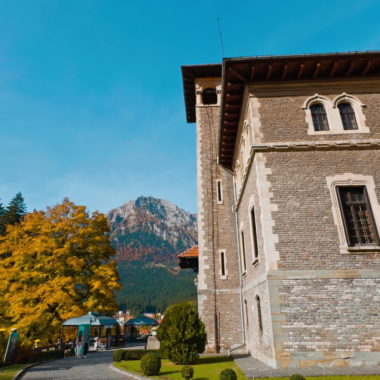 Facciata del vecchio palazzo di mattoni con montagne sullo sfondo. Scenario di un autunno accogliente vicino al castello