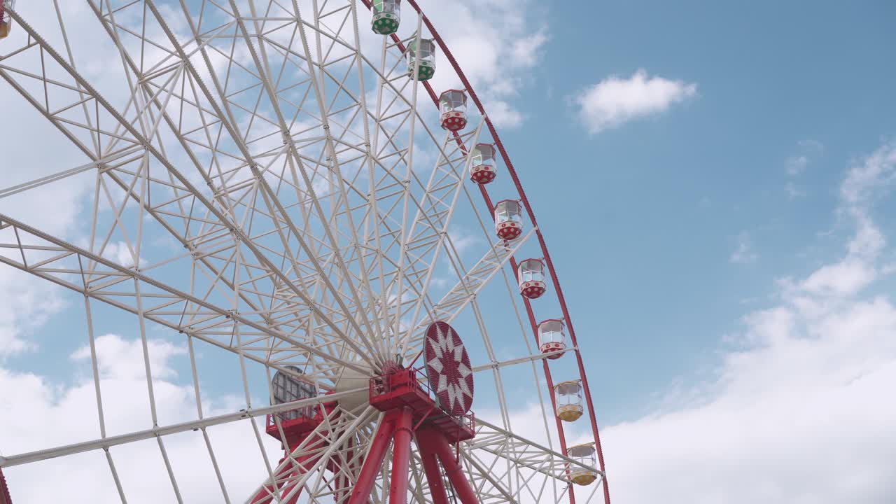 большое колесо обозрения в парке развлечений вращается против облачного неба