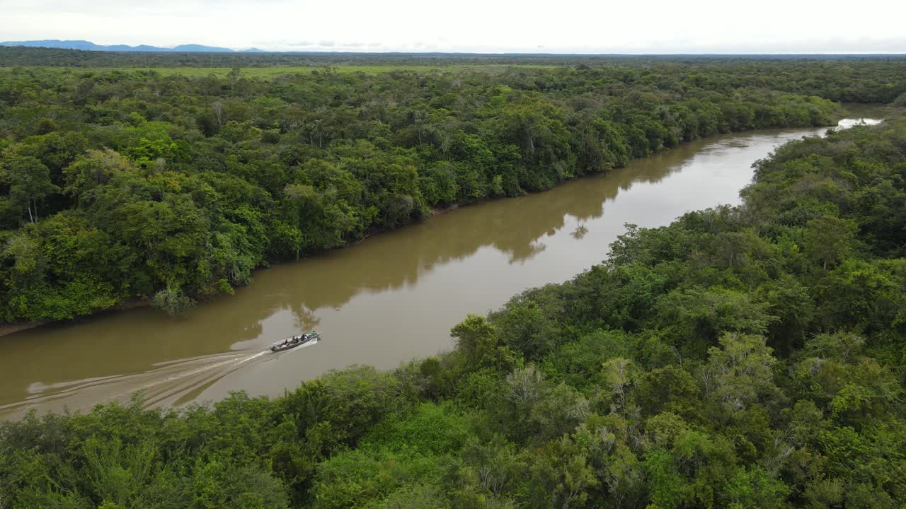 vista aérea cinematográfica, barco navegando en un río fangoso en lo profundo de la selva sudamericana