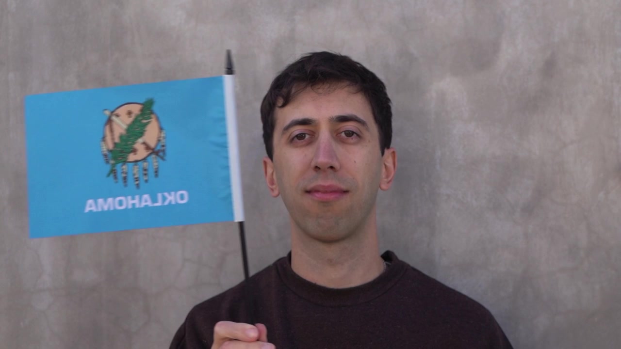 Persona ondeando la bandera del estado de Oklahoma en cámara lenta. Primer plano