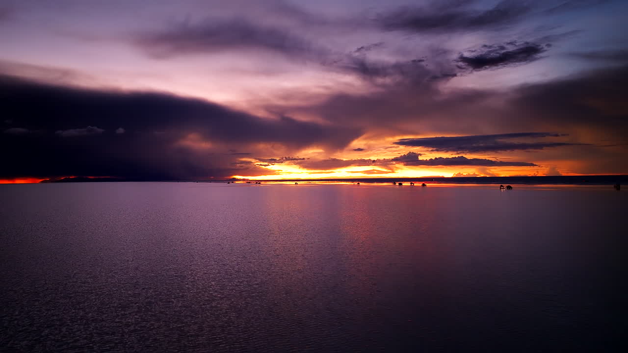 Luftaufnahme eines strahlenden Sonnenuntergangs mit düsteren Wolken über den malerischen Salzseen von Uyuni in Bolivien