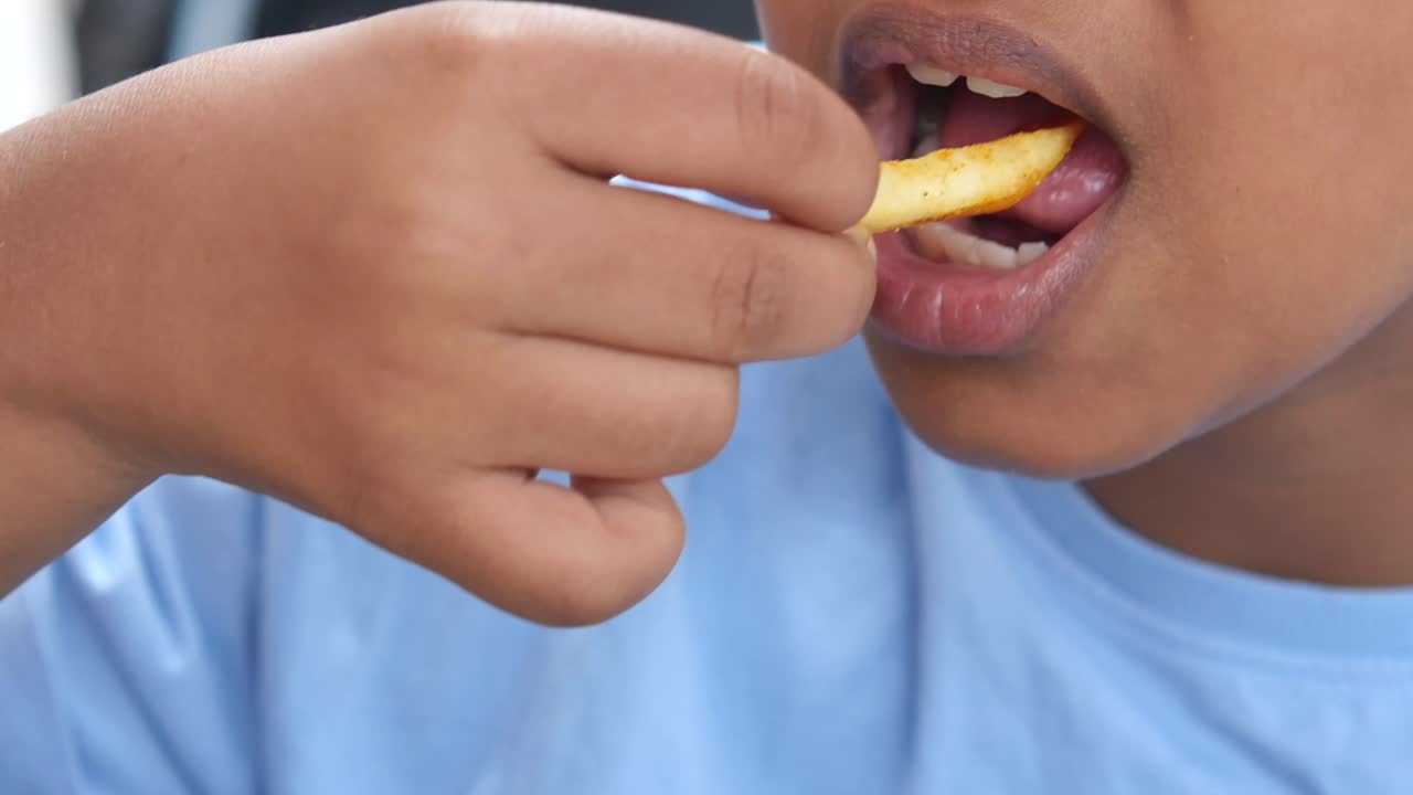 Close-up of a child eating a french fry