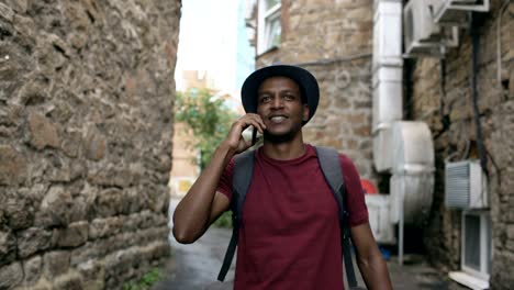 steadicam shot of african american tourist walking and chatting phone. young happy man travelling in europe