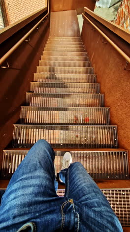 pov man walking down modern metal staircase with rusted side panels, vertical