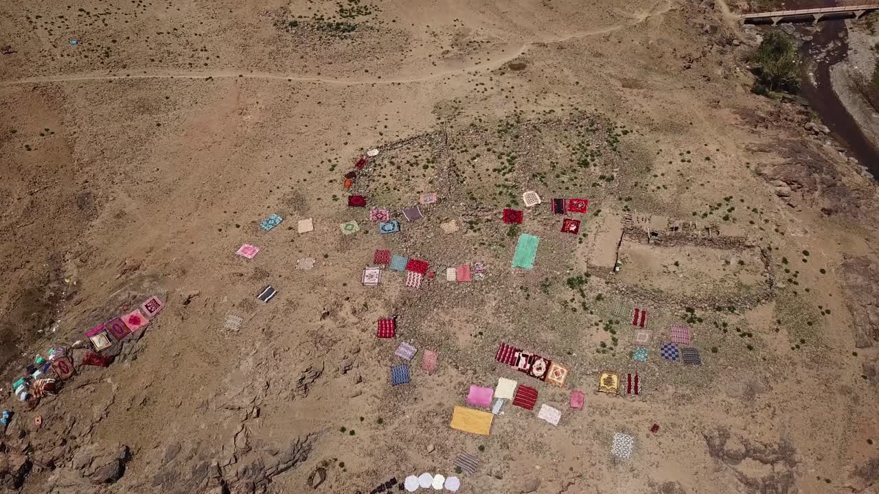 Vista aérea de coloridas alfombras marroquíes secándose en el árido suelo tras el lavado. Las vibrantes alfombras extendidas en Ouarzazate resaltan la vida cotidiana tradicional y la cultura local.