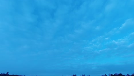 big sky time-lapse: thin clouds drift across deep blue sky at dusk