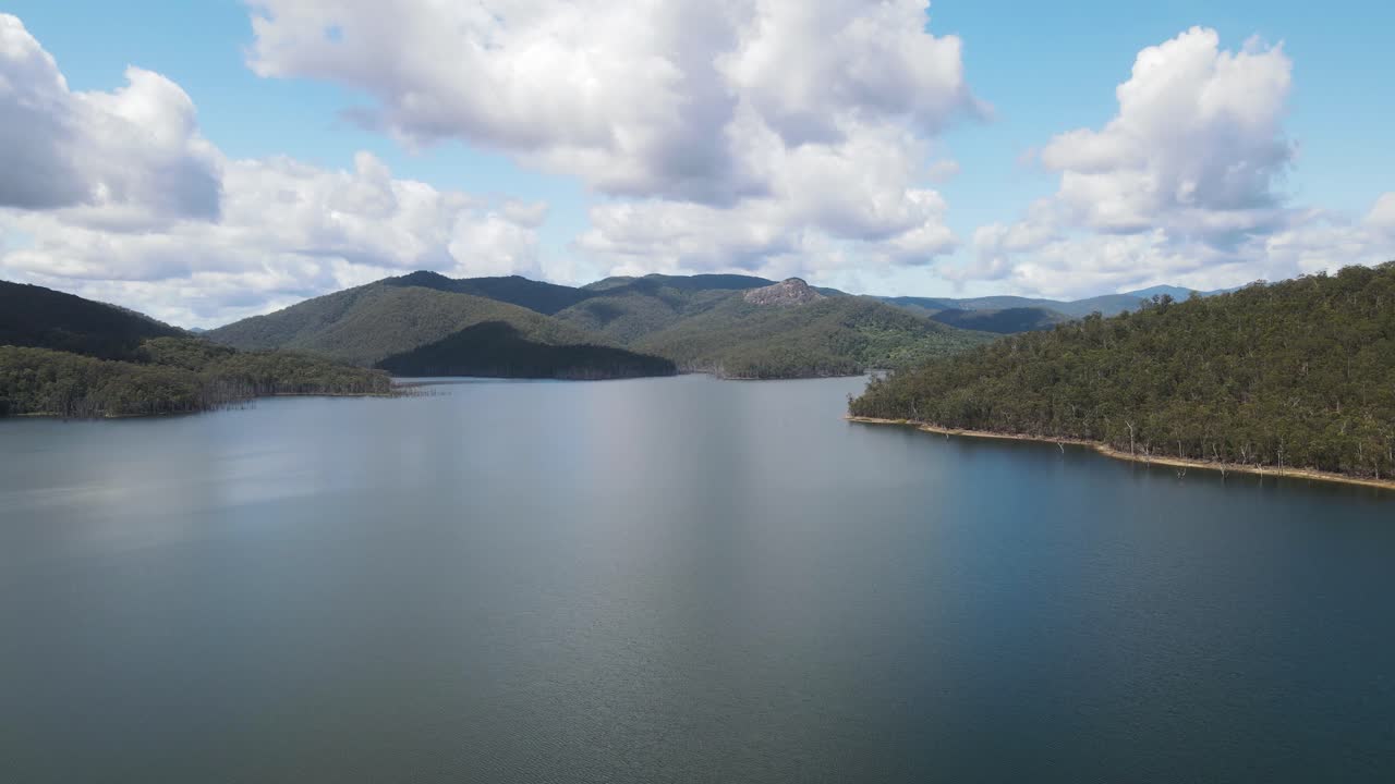 물가 위로 솟아오른 구름 덮인 산맥으로 둘러싸인 큰 홍수 계곡의 경치