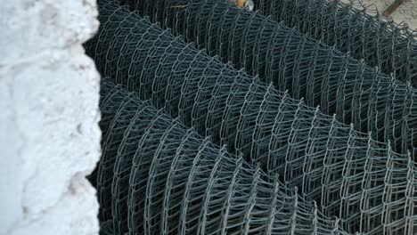 reveal behind wall of stacked wire mesh rolls on floor