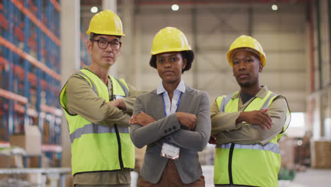 portrait of diverse workers wearing safety suits with arms crossed in warehouse