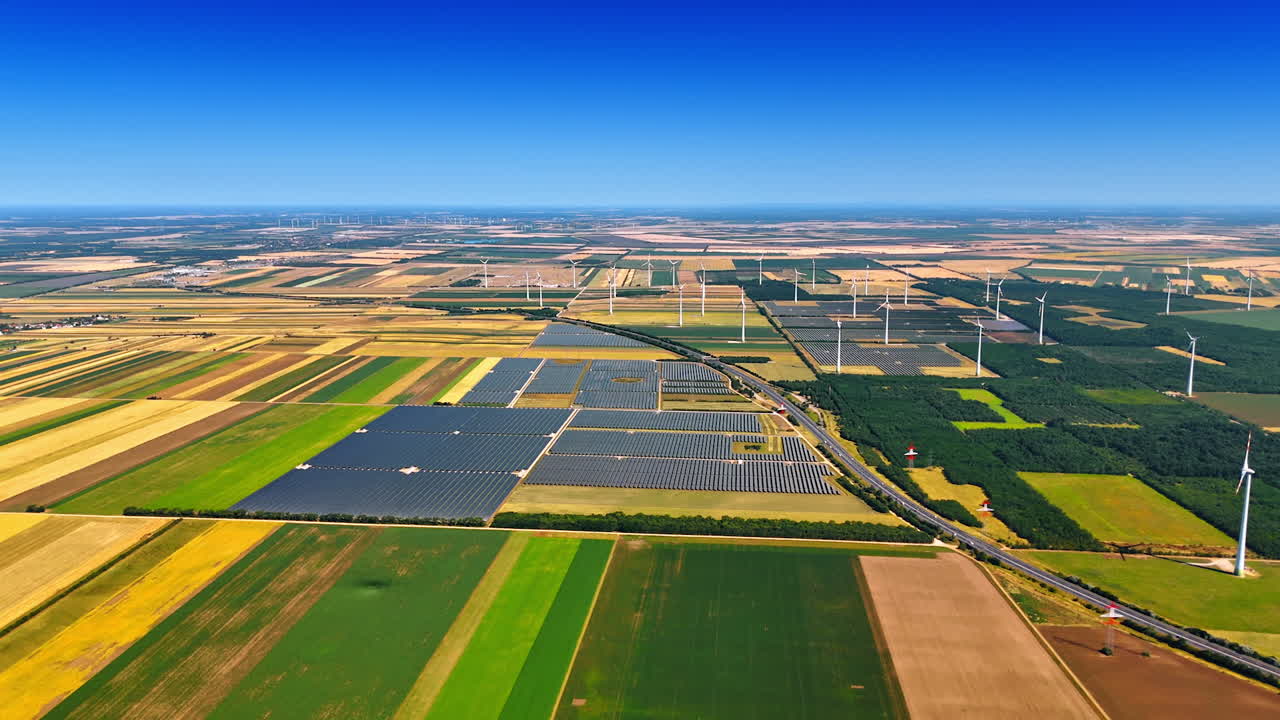 Endless agricultural plantations with solar panel areas and wind farms. Renewable energy concept. Drone footage