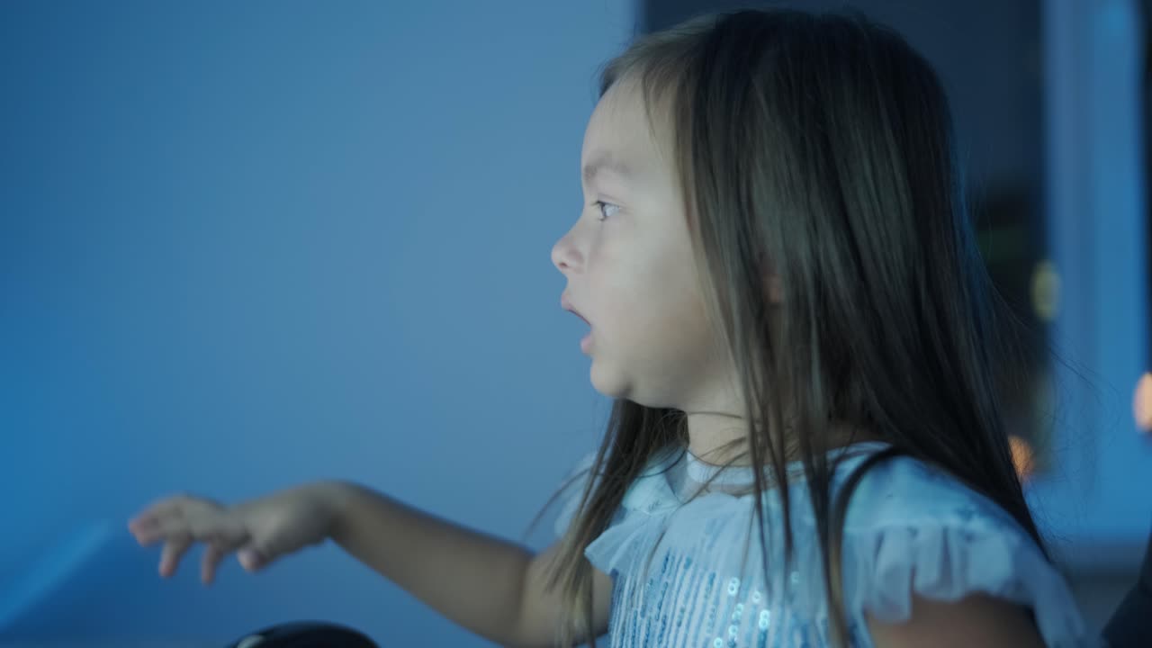 어린 소녀가 컴퓨터 앞에 앉아서 강한 감정을 표시합니다. 이 장면은 편안한 실내 환경에서 펼쳐지는 매력적인 순간 동안 그녀의 표현적 반응을 포착합니다.