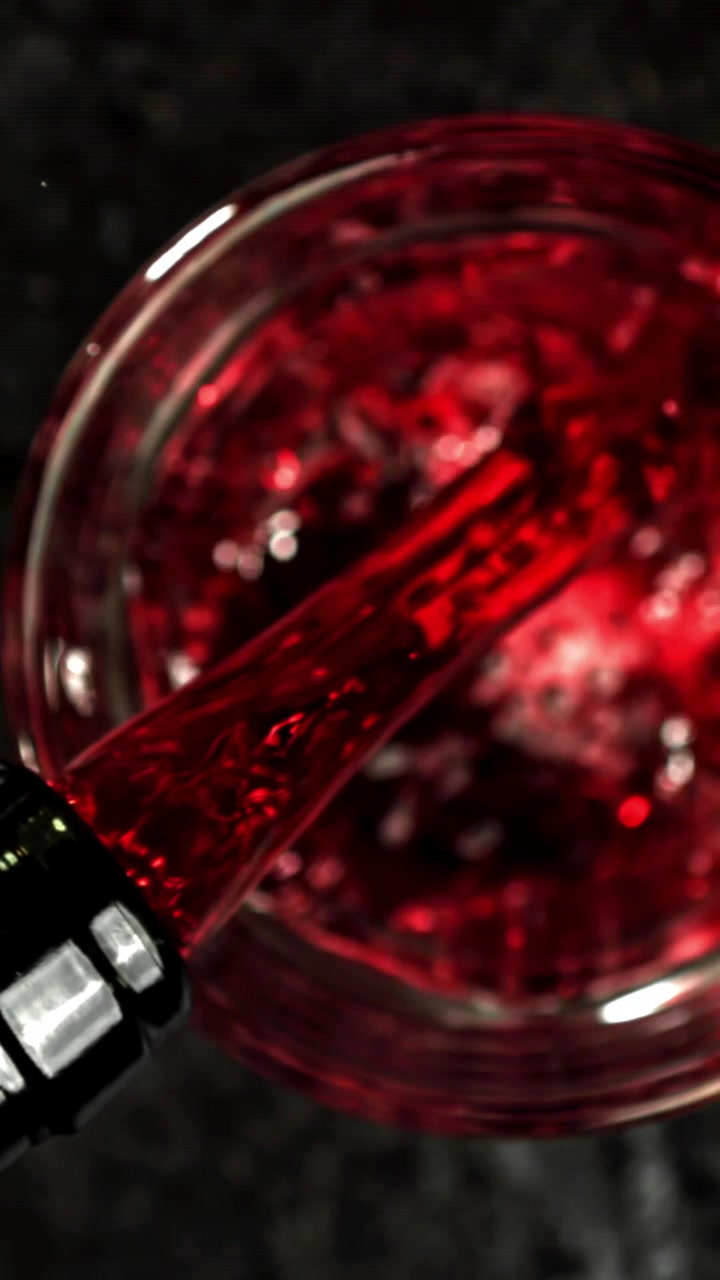 Versamento al rallentatore di vino rosso in un bicchiere dall'alto