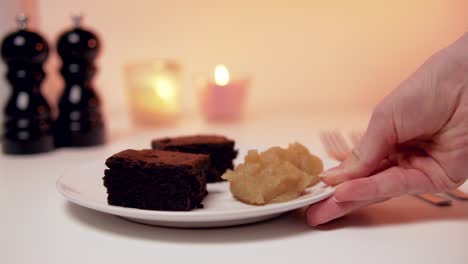 délicieux désert romantique à la recherche : brownies à la compote de pommes sur une plaque blanche avec des bougies en arrière-plan