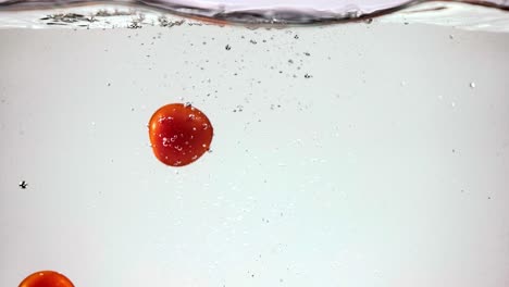 tomates cereza salpicando en el agua