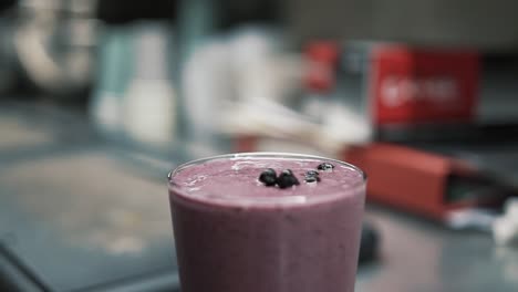 hand adds blueberries and drinking straw into milkshake. handheld