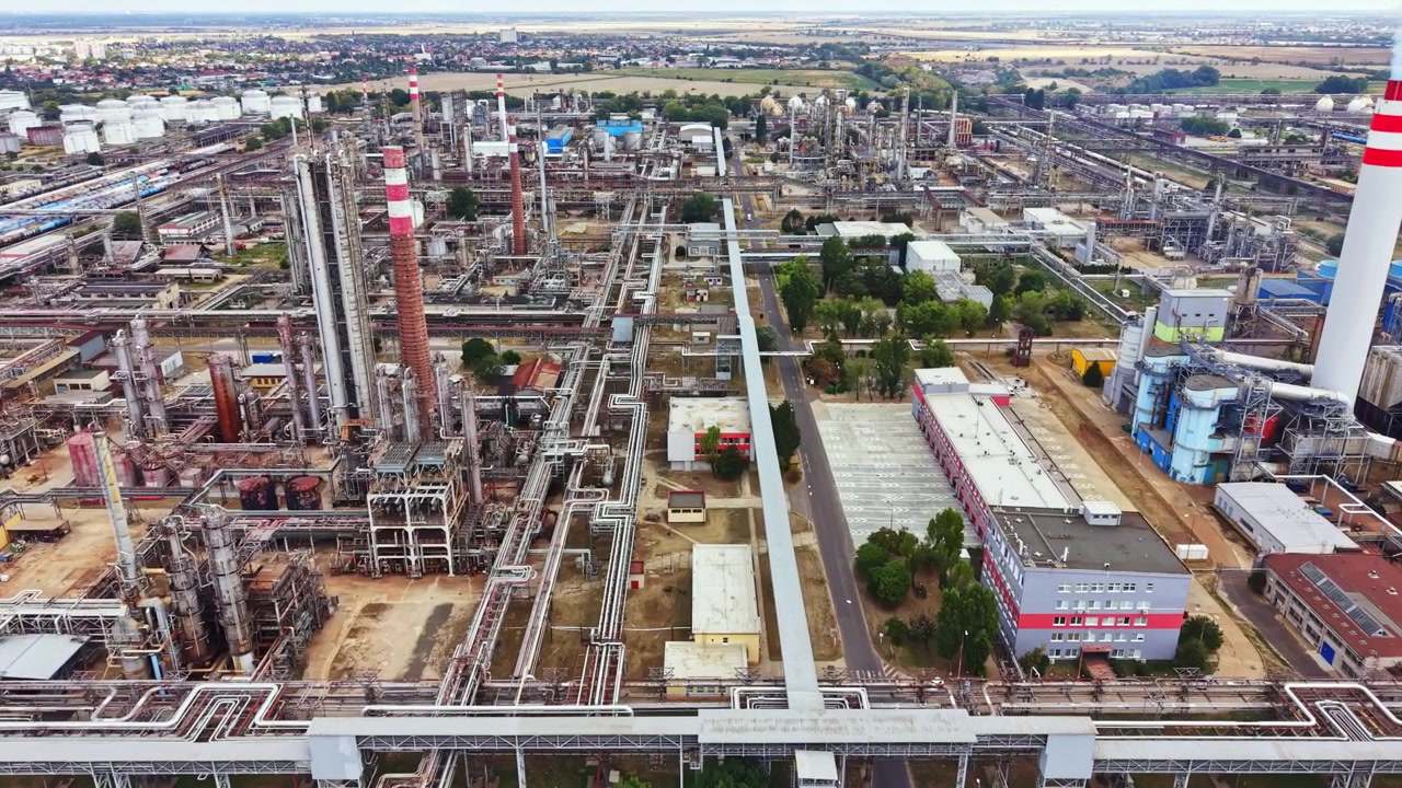 Polígono industrial con muchos edificios, torres y estructuras cerca de la autopista visto desde arriba durante el día con cielo despejado