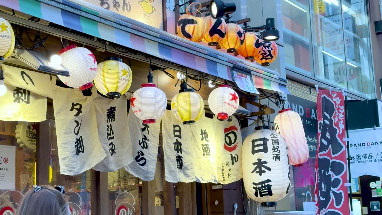 Osvětlené papírové lucerny a látkové závěsy visí před tradiční restaurací na tokijské ulici.