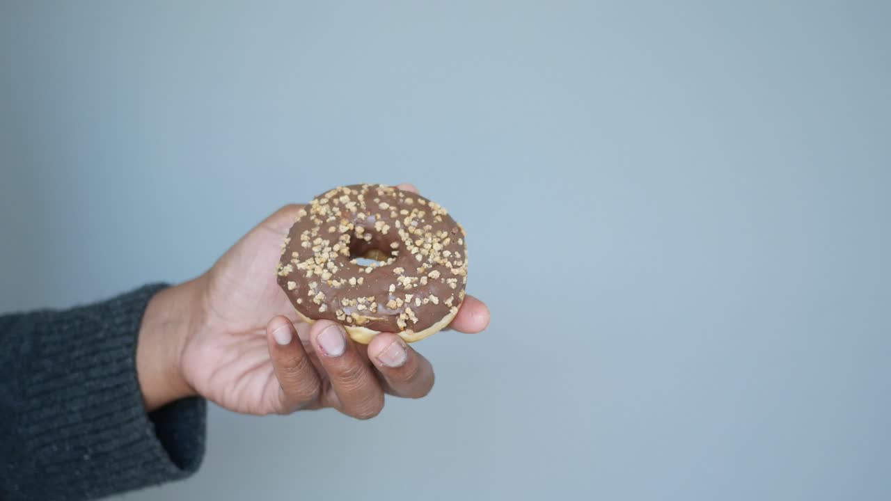 A hand holding a chocolate glazed donut