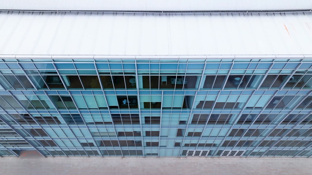 Aerial Glass Office Facade With Windows Showing Repetitive Grid Of Bluetinted Panes, Empty Corridors, Faint