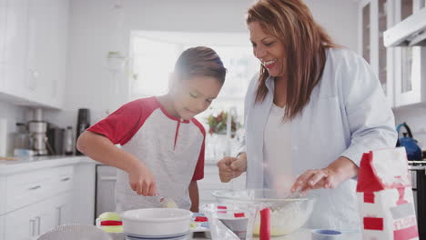Pre-teen-boy-and-his-grandmother-making-cakes-in-the-kitchen,-filling-forms-with-cake-mix,-close-up