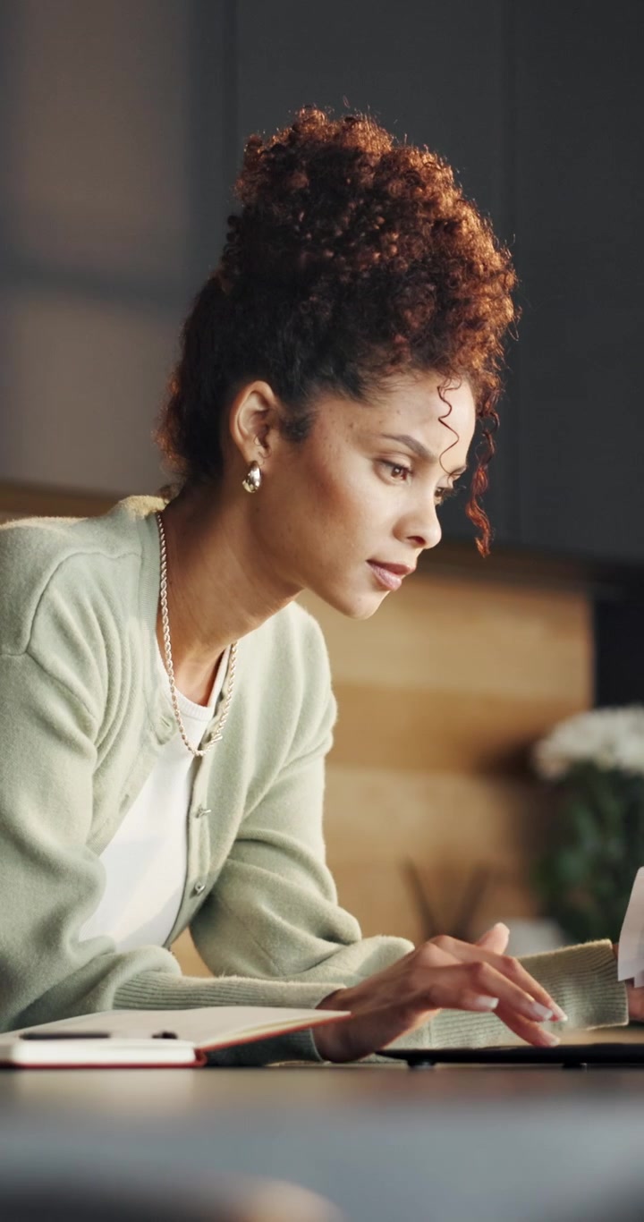 Focused Woman Reviewing Documents and Working on Laptop at Home
