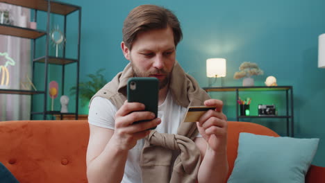 caucasian man using credit bank card and smartphone transferring money purchases online shopping