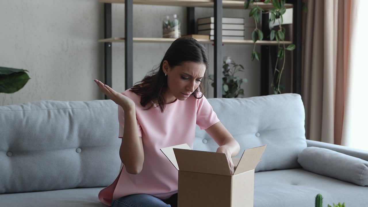 la mujer abre la caja de cartón recibió la mercancía ordenada rota se siente enojada