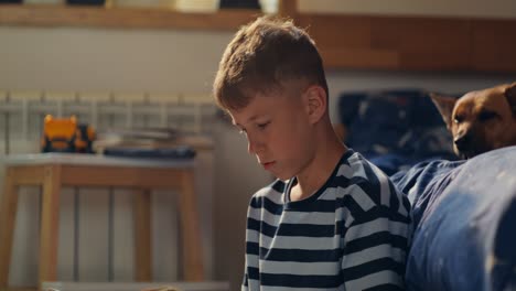boy reading a book in his bedroom with a dog