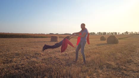 papá dando vueltas feliz hijo sosteniendo sus manos al aire libre