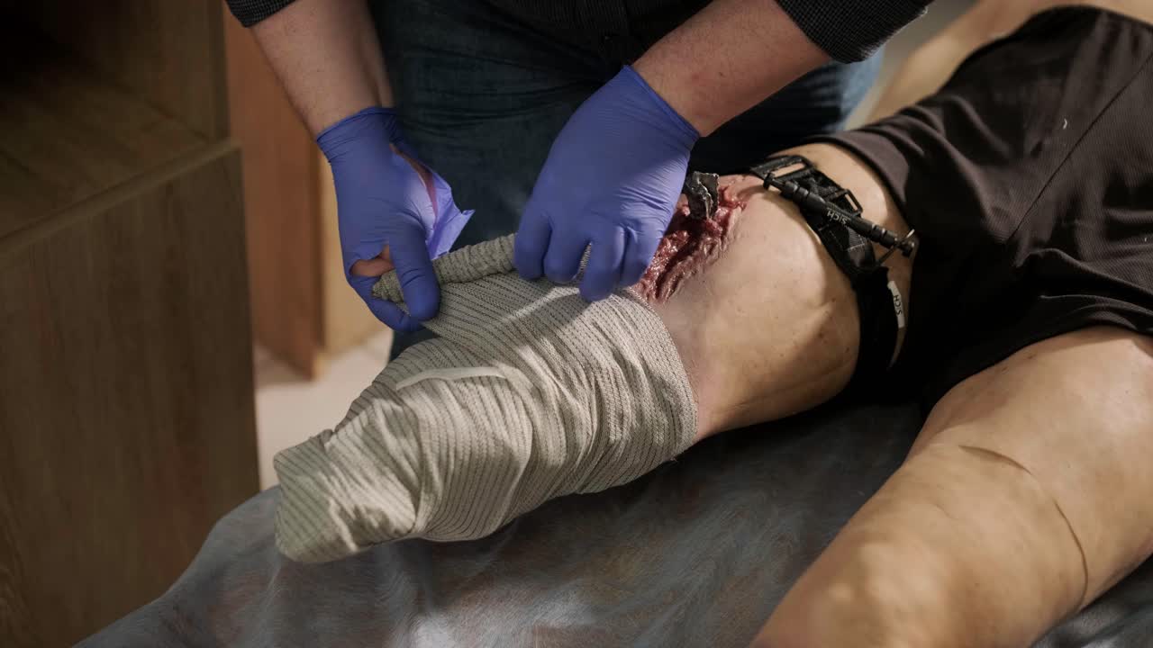 el médico táctico cubre la herida con un vendaje en el maniquí.