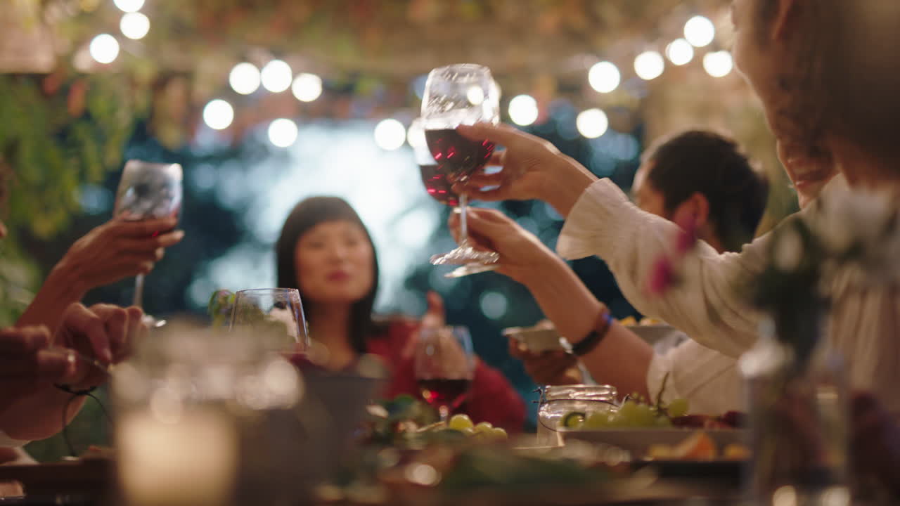 다민족 친구들이 저녁 파티에서 축하하고 토스트를 만들고 와인을 마시며 행복한 재회를 즐기며 채팅하고 음식을 나누고 즐거운 저녁을 즐기며 야외 테이블에 앉아 4k