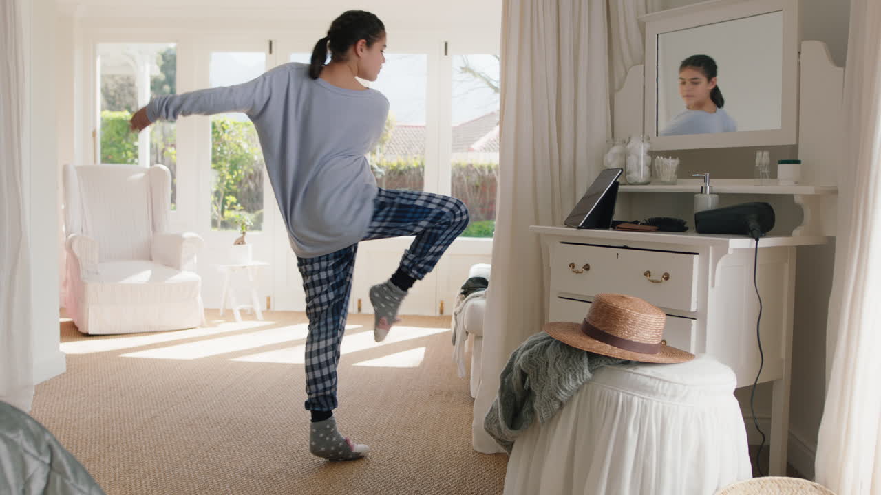 행복한 십대 소녀는 침실에서 발레 춤을 연습하고 리허설하고 주말 아침에 파자마를 입고 재미있는 춤을 추고 있습니다.