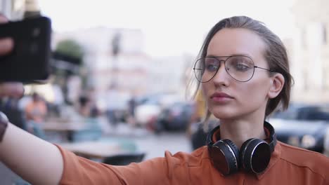 Young-Woman-With-Light-Day-Make-Up-Standing-On-The-Street-And-Taking-Selfie-With-Her-Smartphone