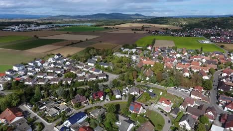 drone flight over the village of oberrimsingen on a cloudy summer day, fields, mountains and a lake in the background